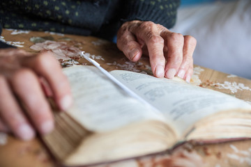 Old woman hands on the open prayer book.