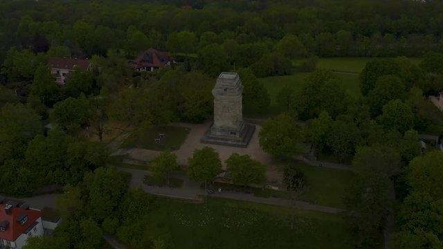 Aerial around the Bismarkturm (Bismark Tower) in spring  in Stuttgart, Germany. Camera  zooms in  towards a small tower on a hilltop and then tilts down as it passes over.