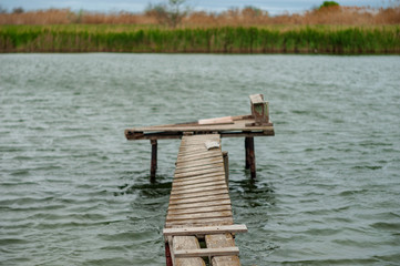 Wooden bridge for fishing on the river is destroyed after winter and spring high water. Notion of...