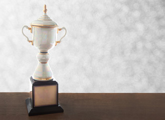 Marble trophy on wooden table on bokeh background. Winning awards with copy space.