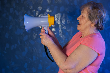 Beautiful senior woman is excited, euphoric, screaming with megaphone, sign of revolution and...