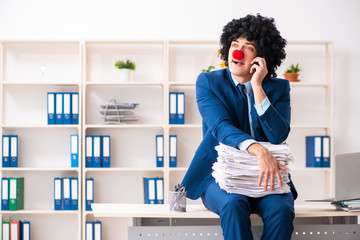 Young clown businessman working in the office 