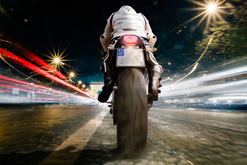 Mann auf Motorrad nachts in der Stadt mit hoher Geschwindigkeit