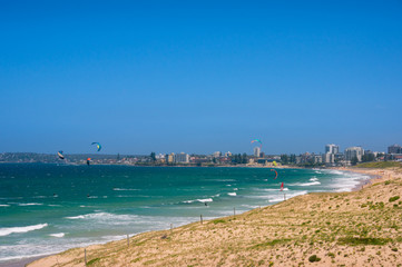 Panoramic beach with colorful kite surfers parachutes