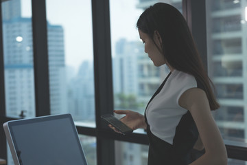 Business Woman talking with mobile phone on her desk in Modern office building