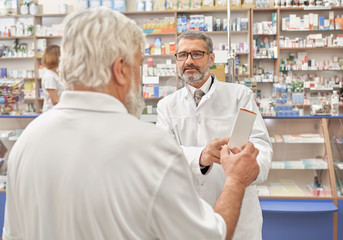 Fototapeta na wymiar Doctor talking with elderly man in drugstore.