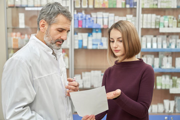Customer consulting with chemist about prescription.