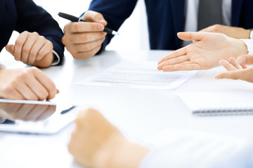 Group of business people and lawyers discussing contract papers sitting at the table, close-up. Successful teamwork, cooperation and agreement concepts