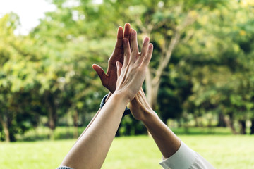 Group of successful people giving hi five together in park