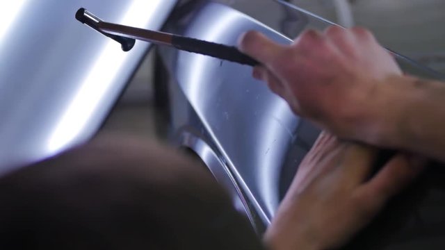 Paintless dent removal. Close up hammer with rubber and machine. Tools for leveling dents without painting. Male master repairs the car in the auto repair shop. Aluminum Hand Tool hammer