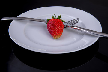 Fruit diet with only one strawberry on a plate
