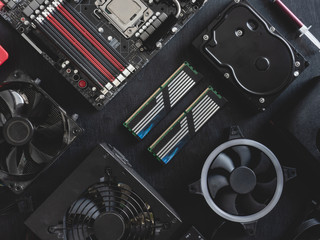 top view of computer parts with harddisk, ram, CPU, graphics card, and motherboard on black table background.