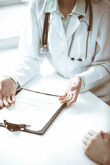 Doctor and  female patient sitting at the desk and talking  in clinic near window. Medicine and health care concept. Green is main color