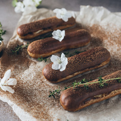Chocolate eclairs on the table sprinkled with cocoa