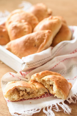 Chicken patty in the foreground on the background of a tray with pies