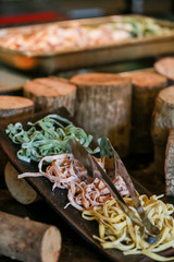 Variety of colored fresh raw uncooked homemade pasta: green spinach, pink beetroot and yellow with flour.