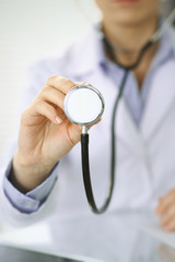 Doctor woman holds stethoscope head, close-up of hands. Physician ready to examine and help patient. Helping and insurance in health care, best treatment and medicine concept