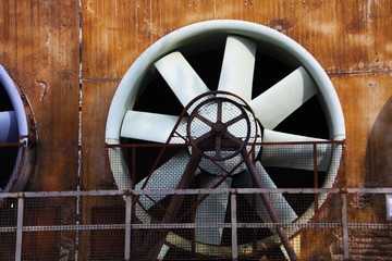 Landschaftspark Duisburg, Germany: Close up of grey turbine with driving belt and rusty steel wall