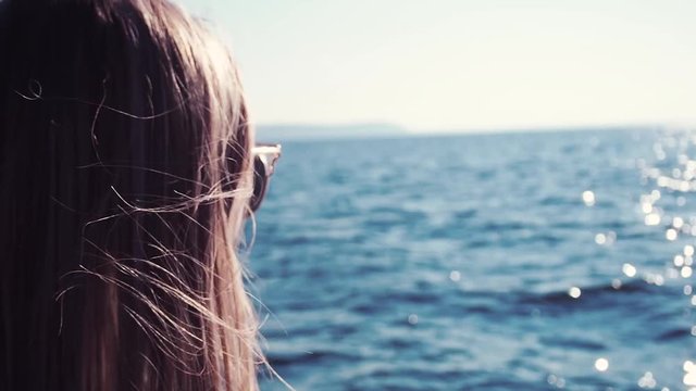 Young woman standing on the ship board and looking into the distance. Summer travel destination