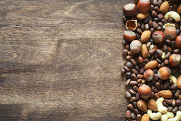 Different nuts on a wooden table. Cedar, cashew, hazelnut, walnuts and a spoon on the table. Many nuts are inshell and chistchenyh on a wooden background.
