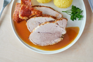 Deutscher Schweinebraten mit Kruste und Knödel auf weißem Hintergrund top view restaurant