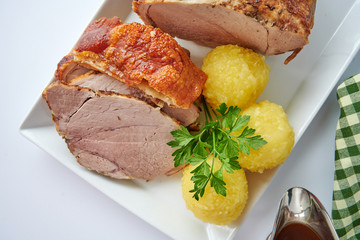 Deutscher Schweinebraten mit Kruste und Knödel auf weißem Hintergrund top view restaurant