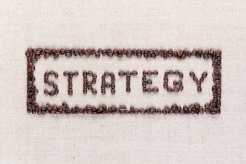 The word Strategy inside a rectangle all made using coffee beans shot from above ,aligned in the center,close up.