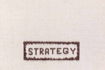 The word Strategy inside a rectangle all made using coffee beans shot from above ,aligned at the bottom.