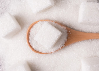 Sugar close-up. Sugar sand and sugar cubes poured from a wooden spoon.