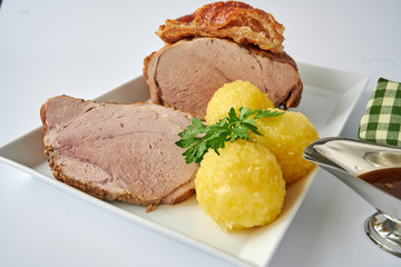 Deutscher Schweinebraten mit Kruste und Knödel auf weißem Hintergrund 