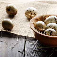 Fresh organic quail eggs in wooden bowl on rustic kitchen table. Space for text