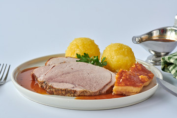 Deutscher Schweinebraten mit Kruste und Knödel auf weißem Hintergrund 