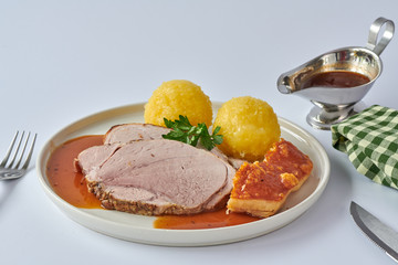 Deutscher Schweinebraten mit Kruste und Knödel auf weißem Hintergrund 