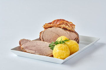 Deutscher Schweinebraten mit Kruste und Knödel auf weißem Hintergrund 