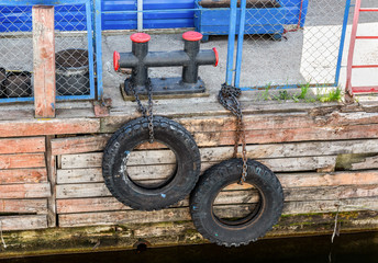 Fototapeta premium Mooring metal bollard with a tires at the pier