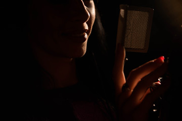 Woman singer singing a song in the recording studio.