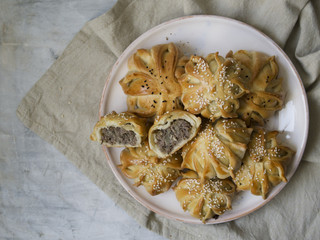Interestingly shaped fresh meat mini pie. Delicious samosa pies with meat on plate on gray background. Piece of pie. Menu, restaurant, recipe concept. Selected focus, close up, copy space.