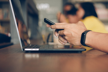 Businessman using laptop and typing on mobile smart phone, business people with technology concept. Close up hand man working at modern workplace using notebook computer and cell phone reading message