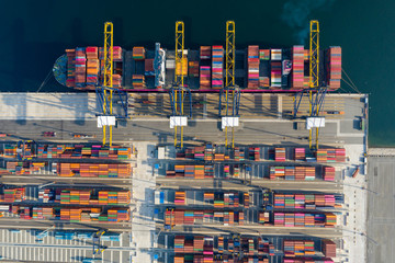 Aerial view. Container ship in pier with crane bridge carries out export and import business in the open sea. Logistics and transportation