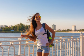  Woman, sunglasses, white shirt, jeans shorts, backpack, city