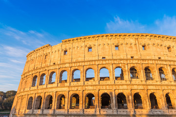 Fototapeta premium The Colosseum in Rome at golden sunrise with blue sky, Italy
