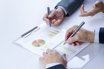 Two businessmen or analysts reviewing financial statement report on Return on Investment, ROI, or investment risk analysis and business performance.