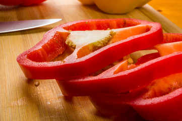 sliced fresh red paprika, bell pepper on bamboo cutting board