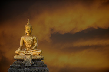 A peaceful superimposed and double exposure images of Golden Buddha statue from Wat Pathum Wanaram, Bangkok, Thailand and pink clouds. Buddha statue is posing “The attitude of subduing Mara".