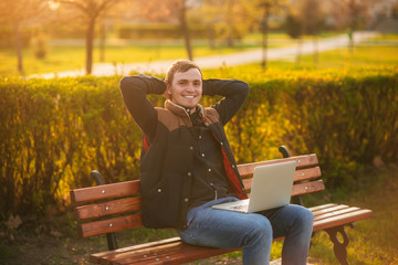 Young businessman finish work on his laptop in the park. Work in internet. Online business