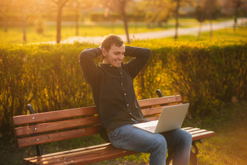 Young businessman finish work on his laptop in the park. Work in internet. Online business