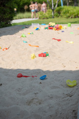 Colourful plastic toys with various shapes and kinds left unattended on a sand box in a resort, waiting for kids to come and enjoy them in a morning.
