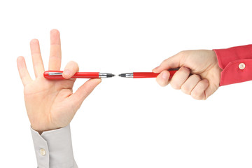 two hands with red writing pens facing each other on white background