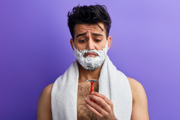 emotional guy isn't satisfied with a razor. close up portrait. sad man has broken the shaver
