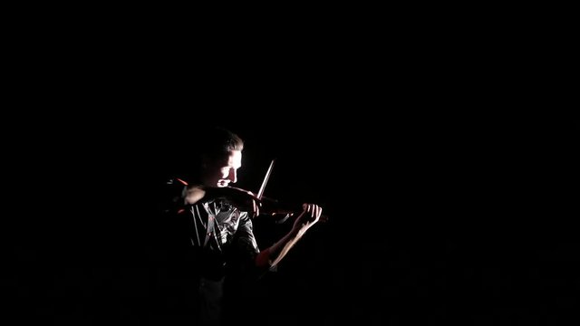 young handsome man plays electric violin on black background, isolated